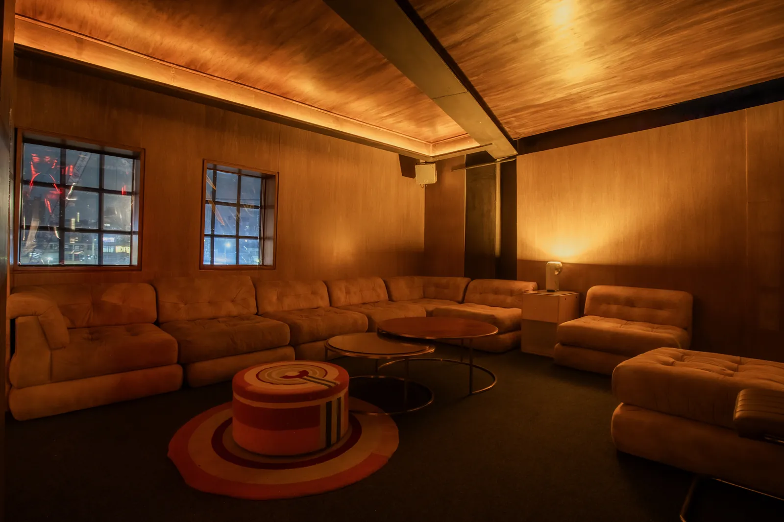 Rincón de Collector's Lounge: sofás curvos junto a ventanas con luz roja