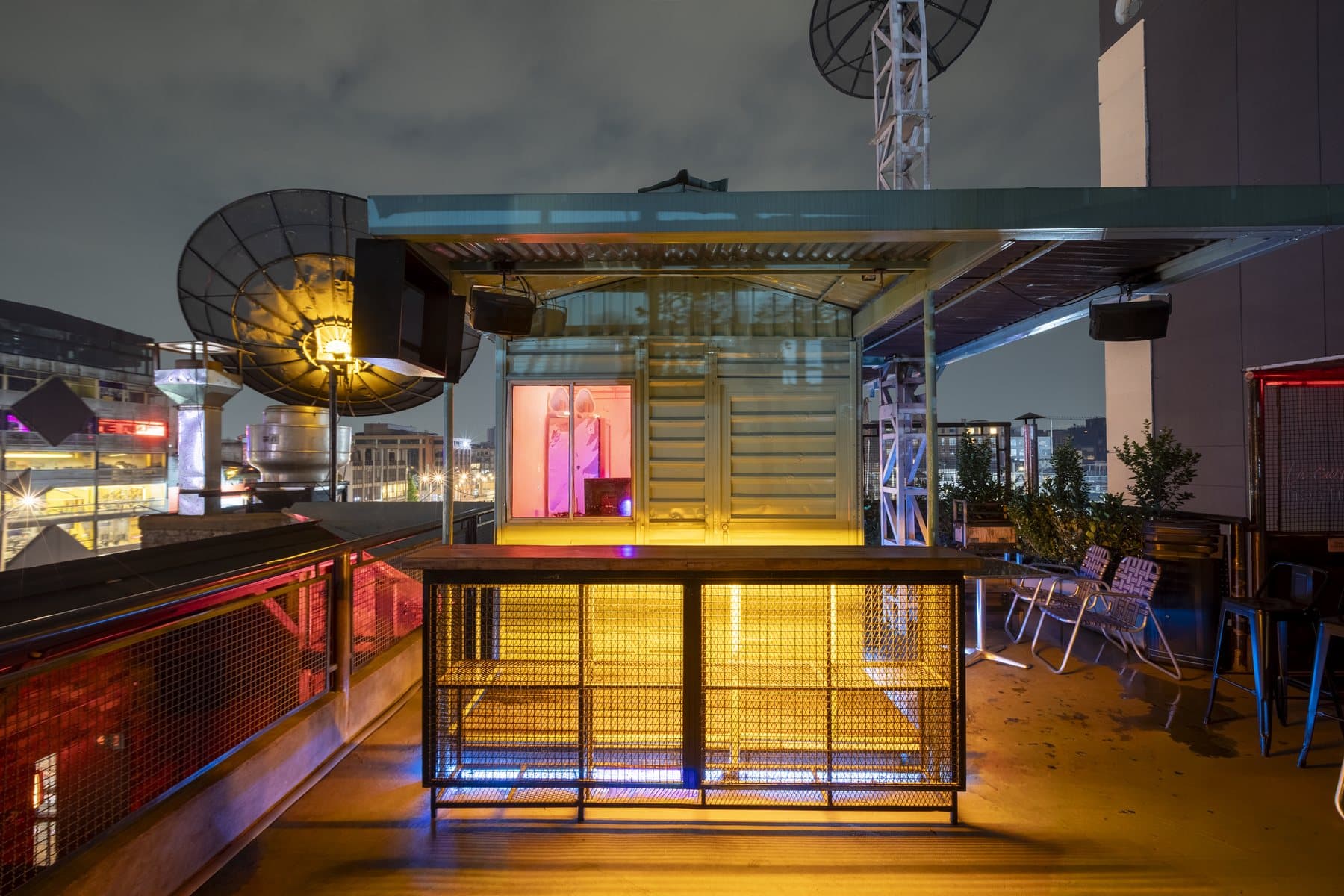 Terraza urbana de Antenna de noche, con la antena parabólica iluminada y las estructuras metálicas del edificio