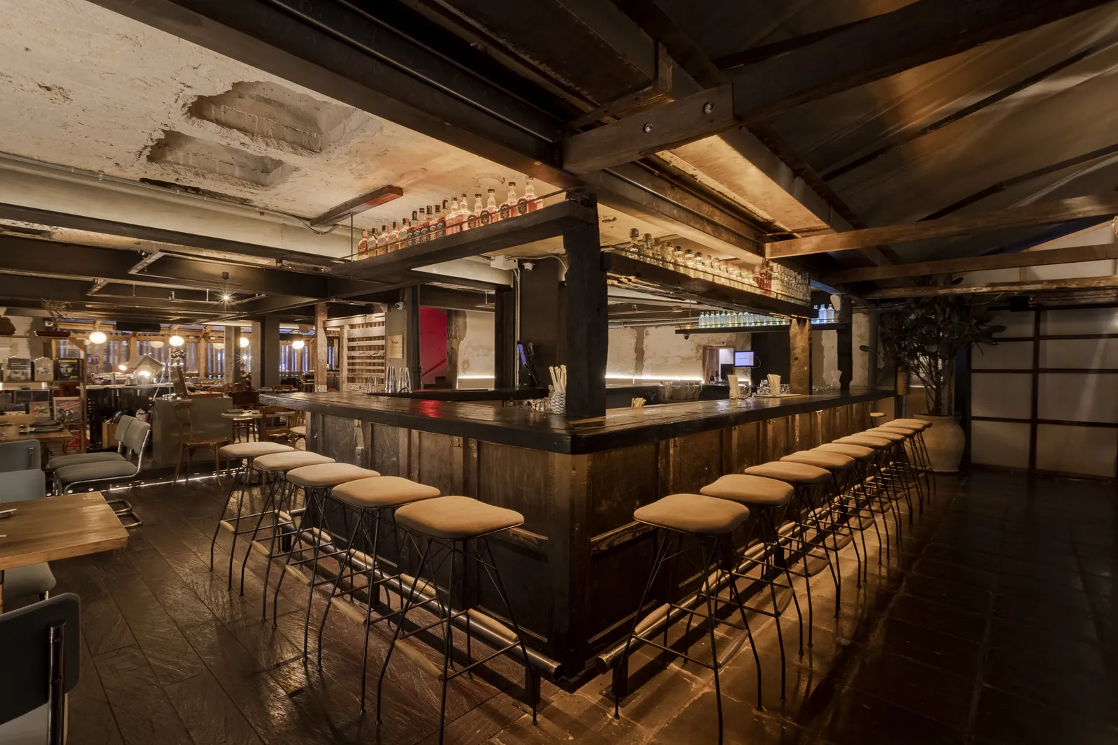 Barra larga de Izakaya con taburetes y botellero retroiluminado