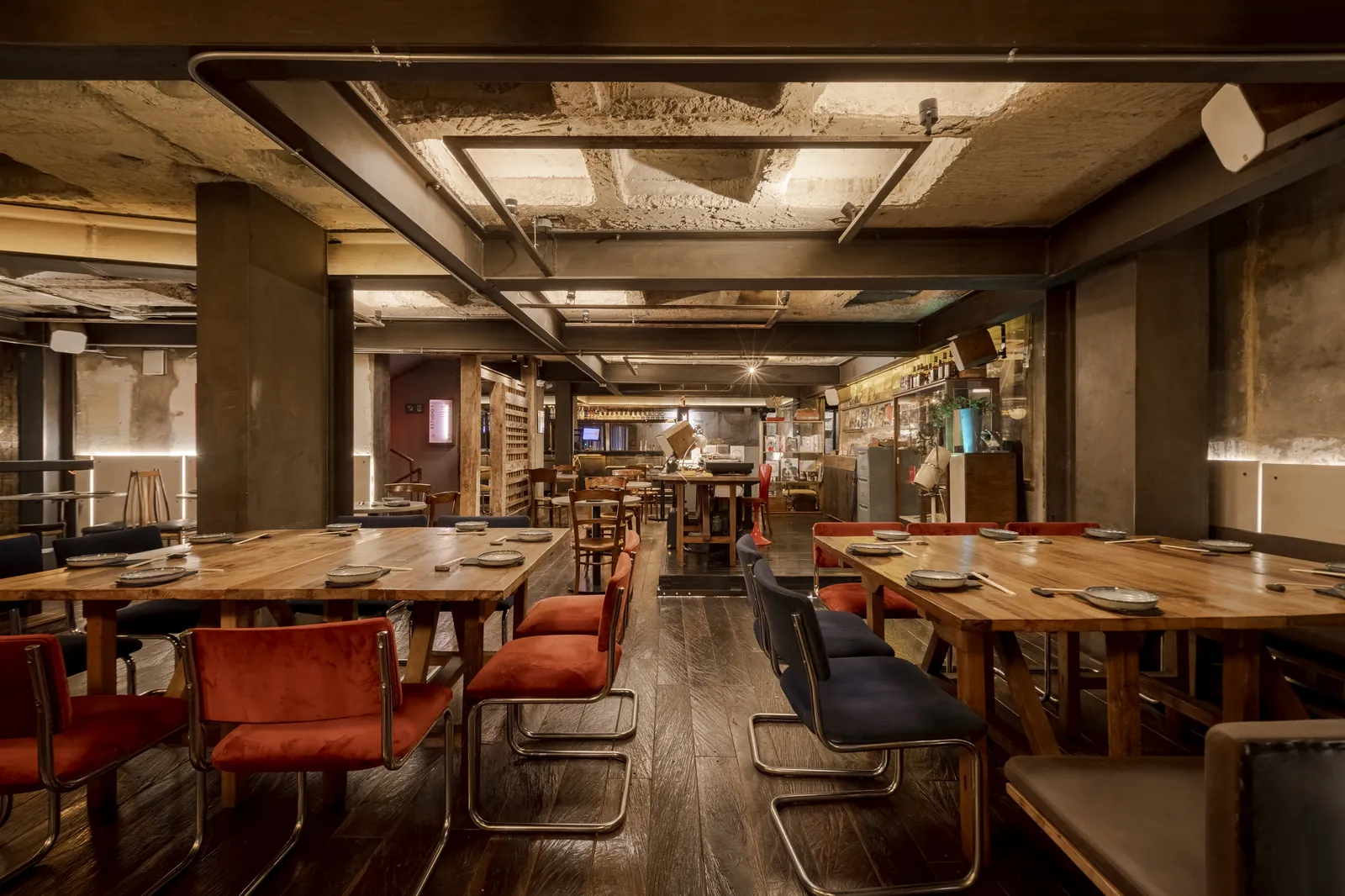 Comedor de Izakaya: mesas servidas, sillas rojas y barra al fondo